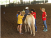 Child riding a horse with women walking it around the arena