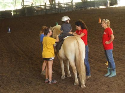 Employees help child on a horse